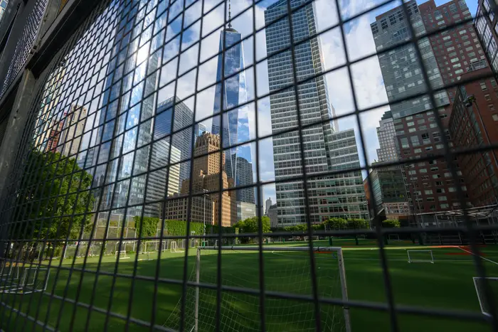 The Battery Park Ballfields remain closed and seen through a fence with skyscrapers of lower Manhattan in the background